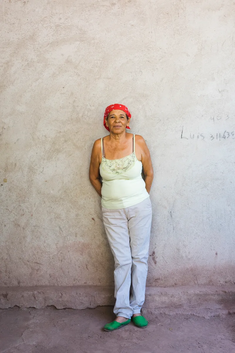 A woman in a red headscarf outside her home