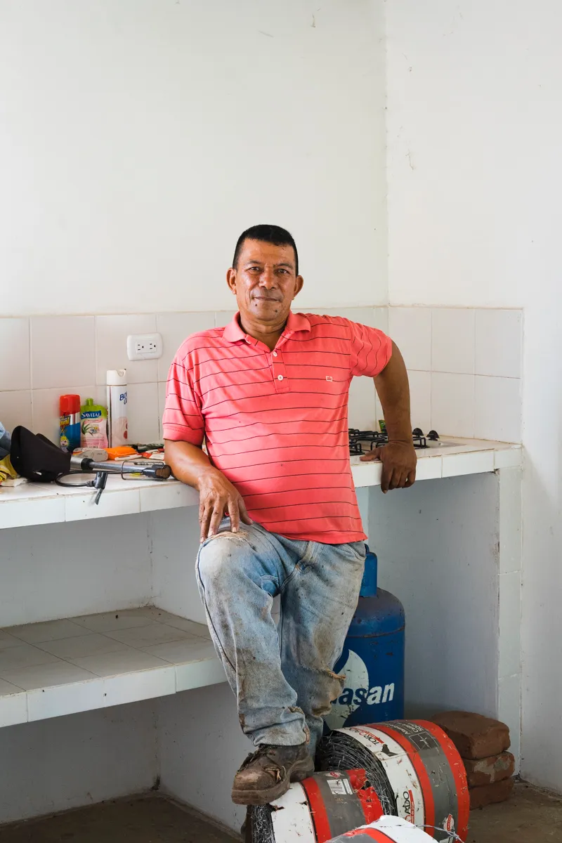 A farmer in his kitchen, a roll of barbed wire at his feet