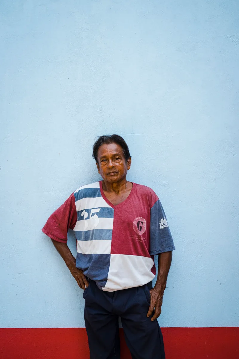 A farmer leaning against a pale blue wall