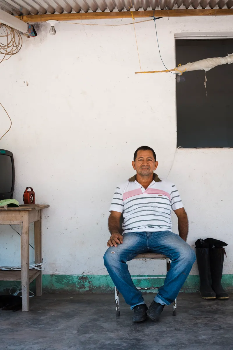 A farmer seated at home beside his rubber boots