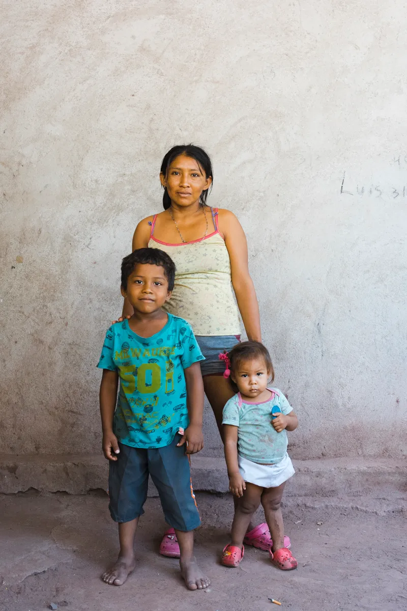 A young mother with her two children against a bare wall