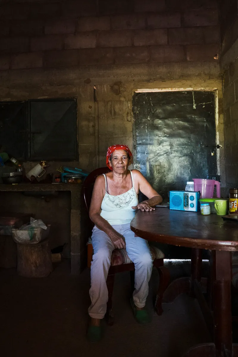 A woman in a red headscarf at her kitchen table