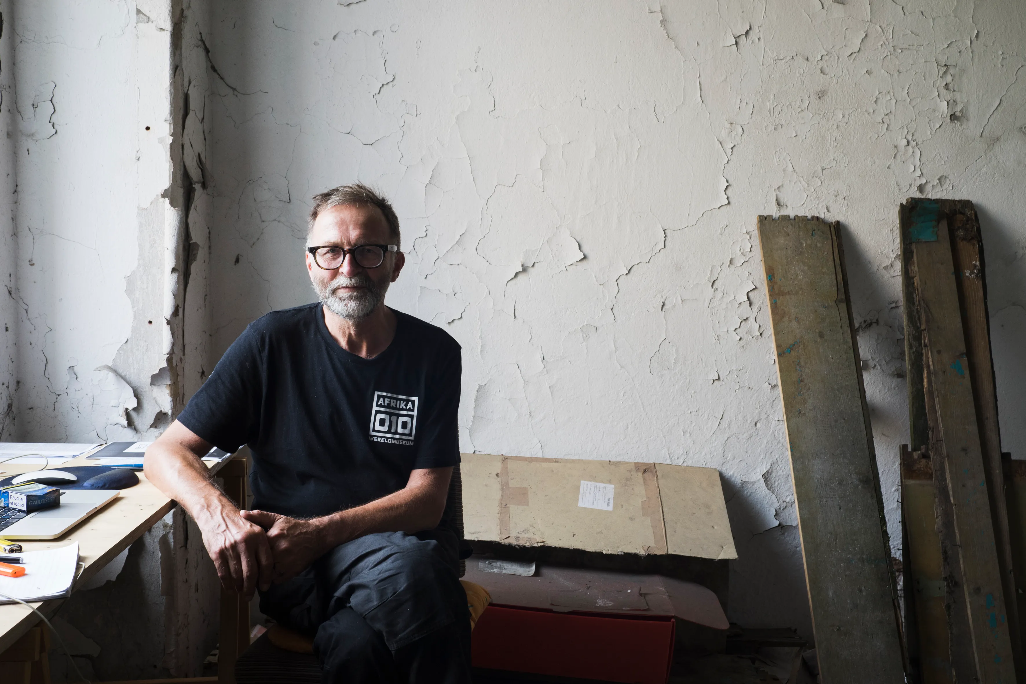 An artist at a makeshift desk against a wall of peeling paint