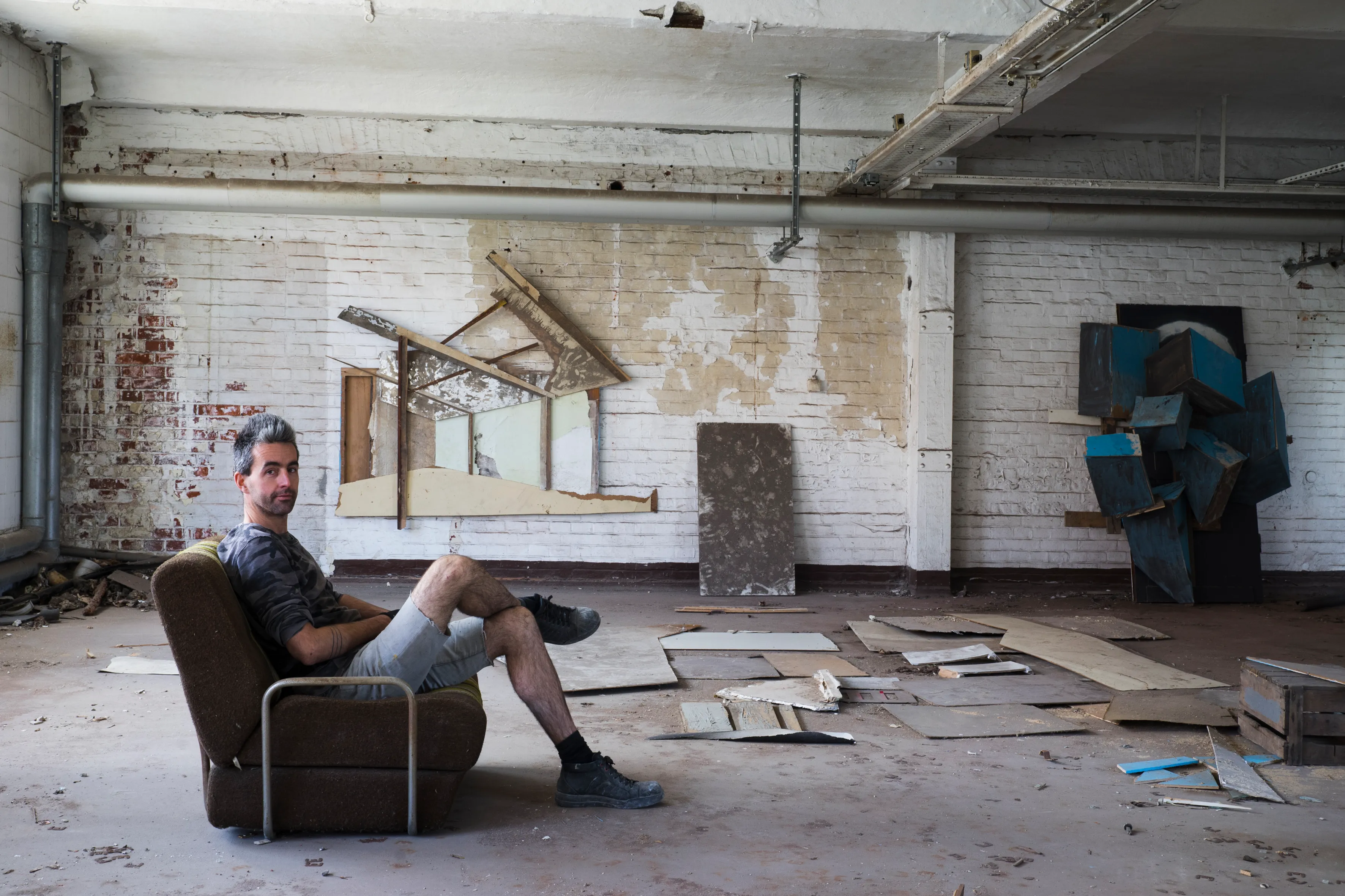 An artist resting in an armchair amid his installation