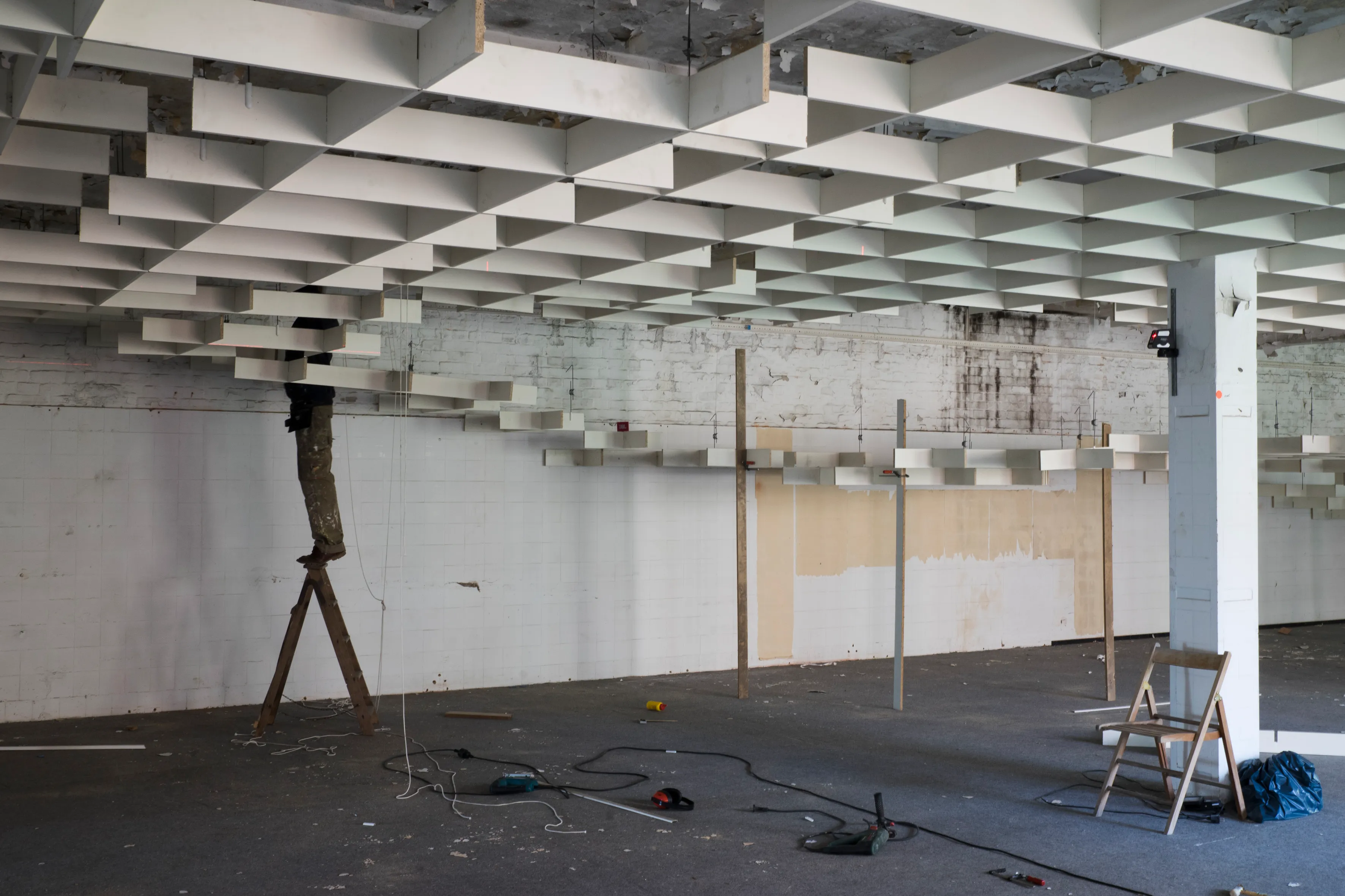 A grid of white beams suspended across a tiled hall