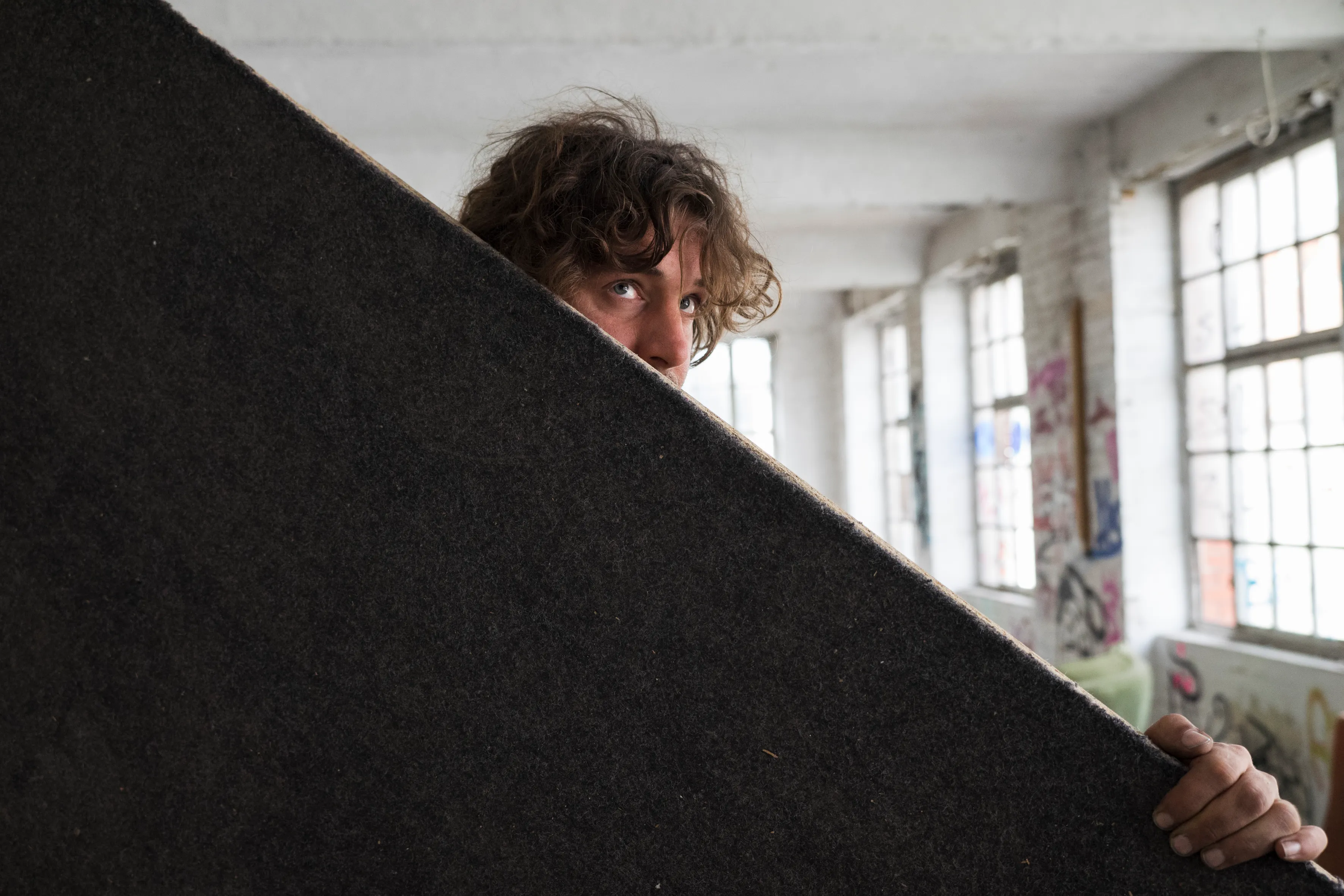 An artist carrying a large felt-covered panel