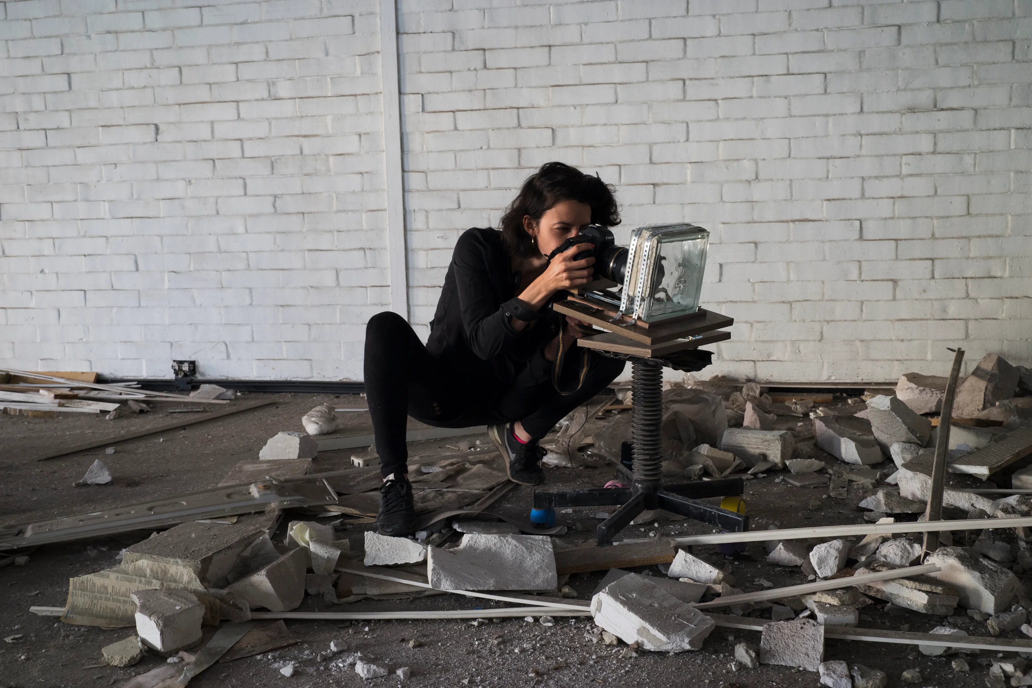 An artist photographing a glass block amid rubble