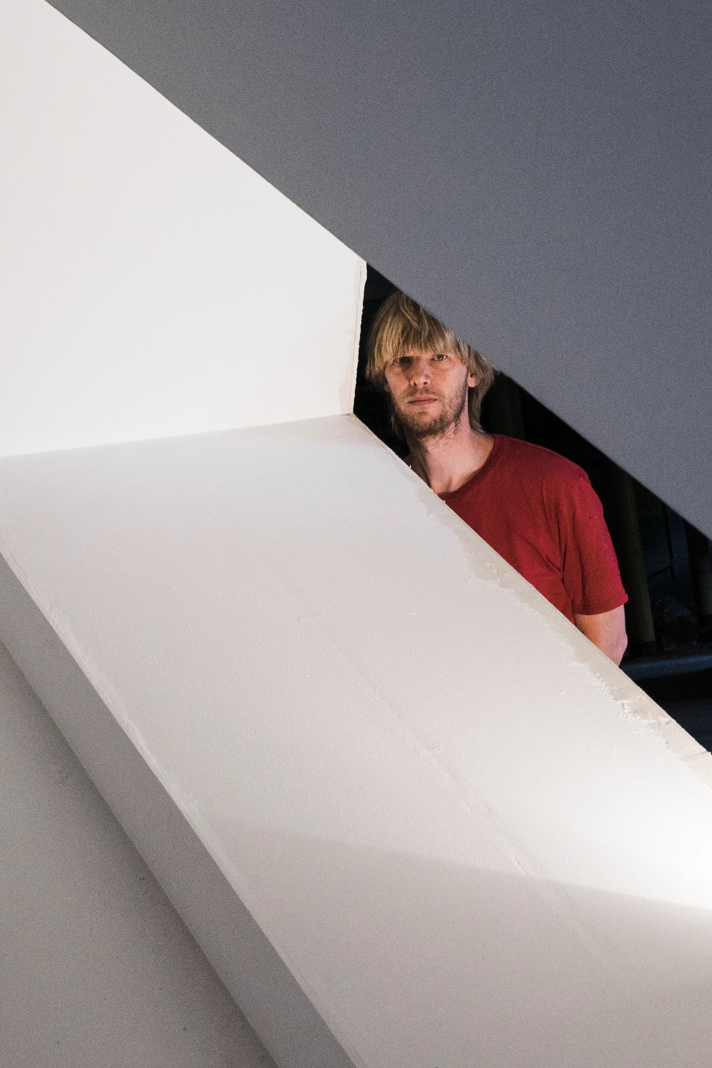 An artist framed by the white panels of his sculpture