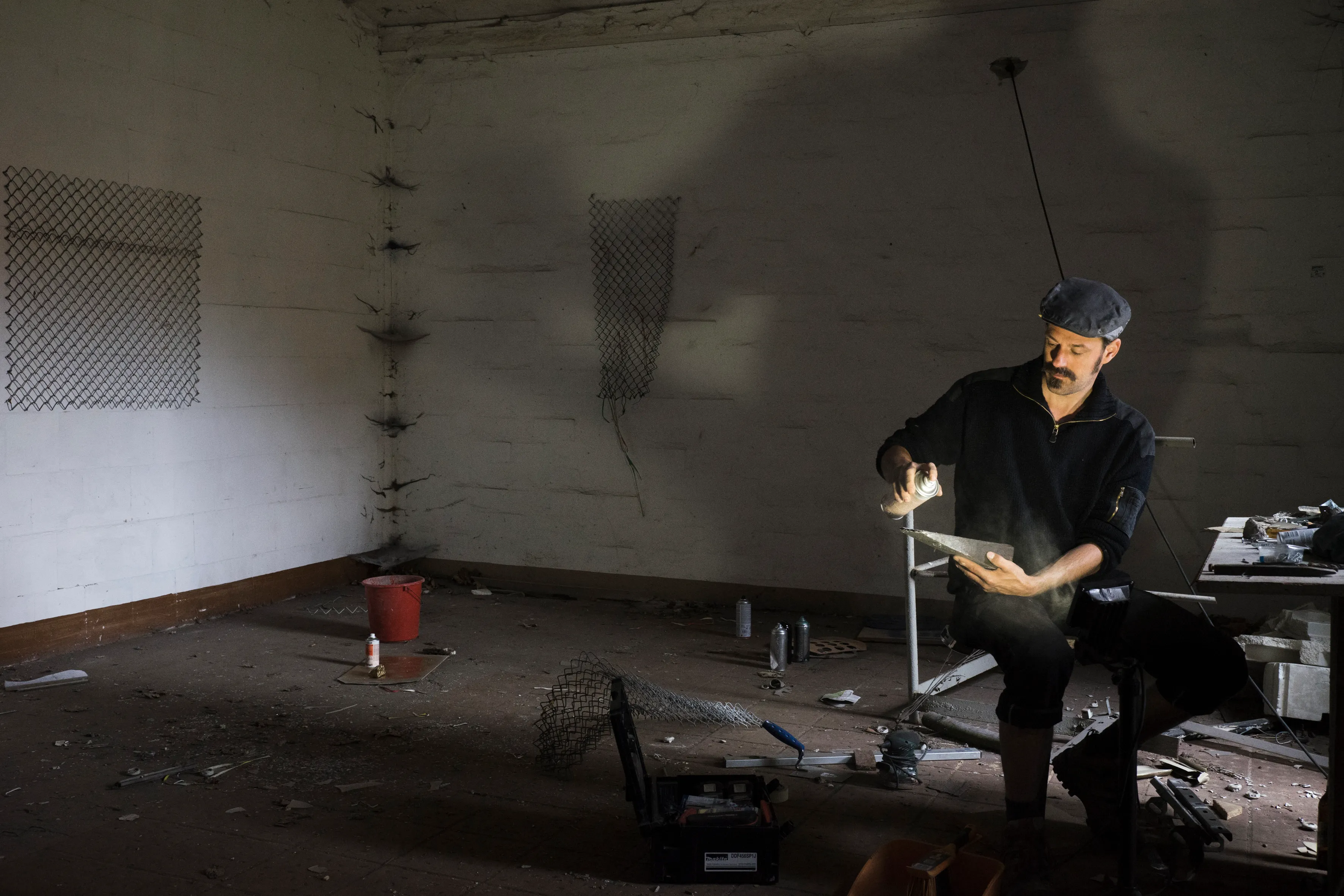 Spray-painting a wire-mesh piece in a bare room