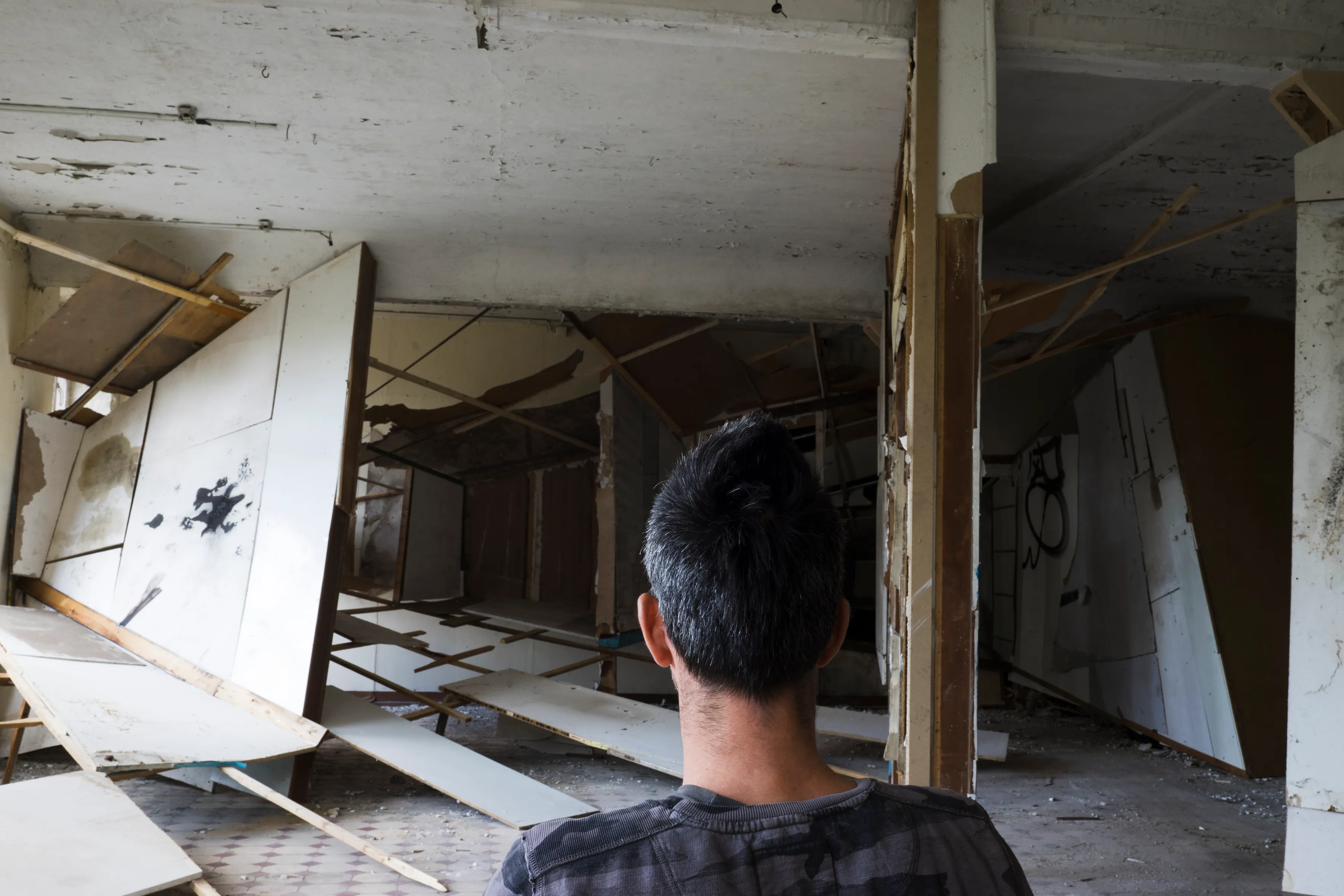 An artist looking down a corridor of leaning panels